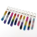 Chainmail Full Persian weave bag charms in ten different Pride flag colors displayed on a white background. Flags shown are AroAce, Asexual, Bisexual, Gay, Genderfluid, Lesbian, Nonbinary, Pansexual, Progress Pride, and Transgender. Each chain hangs from a silver-toned metal swivel clip.